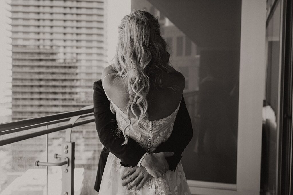 A black and white photo showcases newlyweds embracing on the balcony of the Cosmopolitan before their Las Vegas elopement