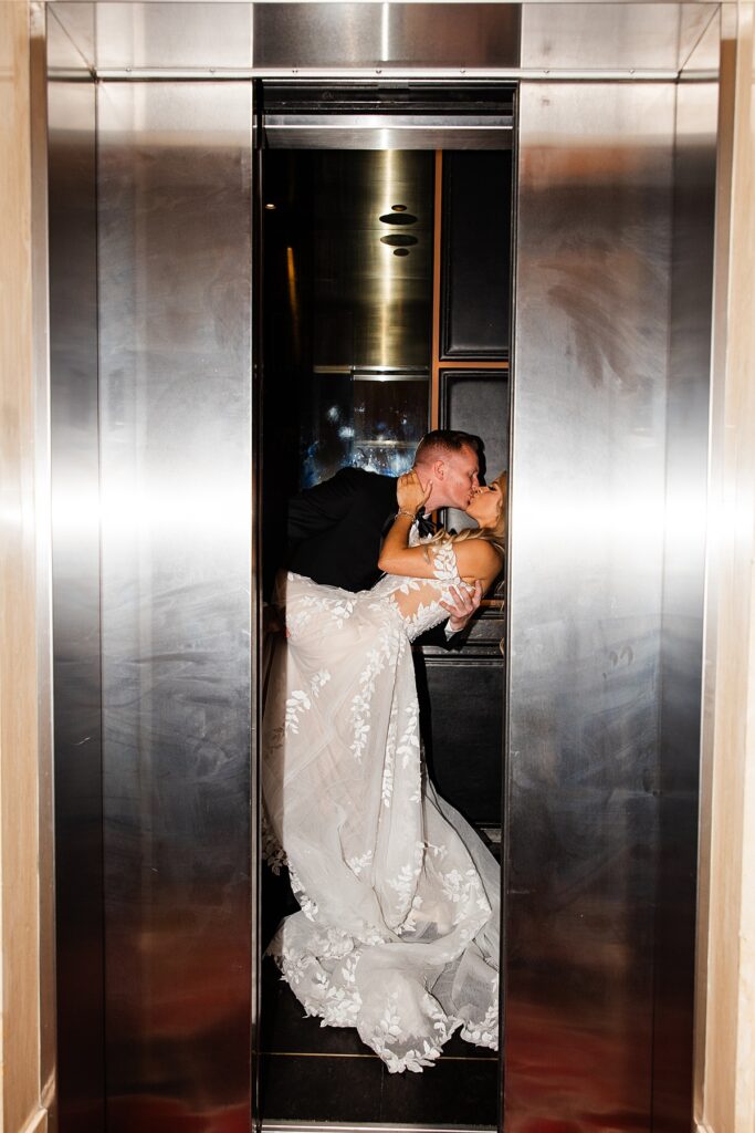 Newlyweds share a kiss in an elevator following their ceremony at lakeside wedding and events