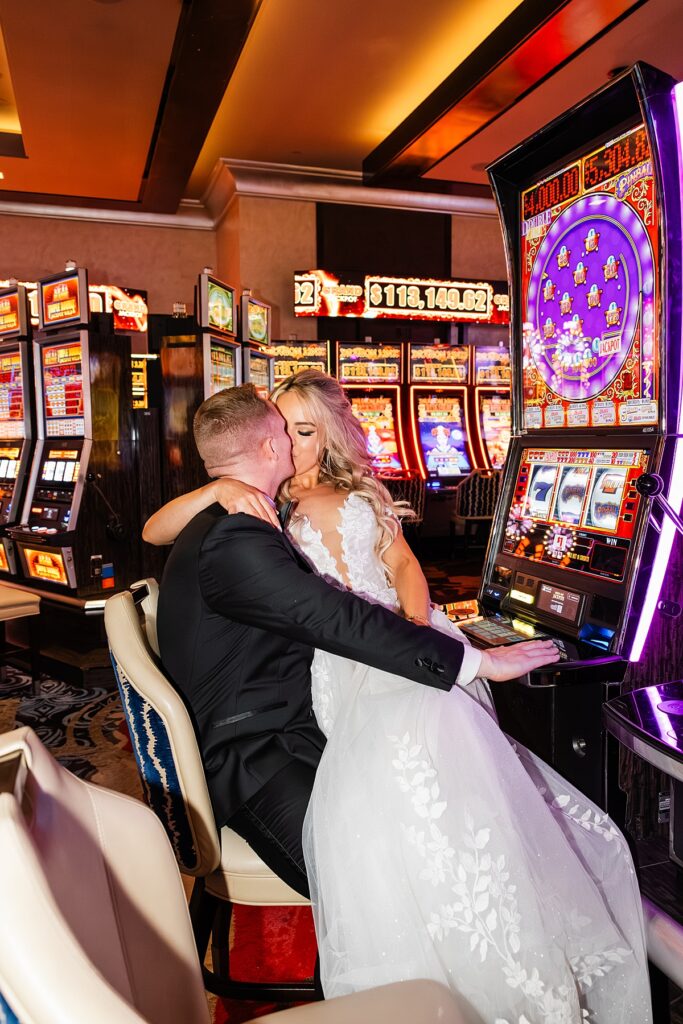 A bride and groom share a kiss by the slot machines during bridal portraits while eloping to Las Vegas