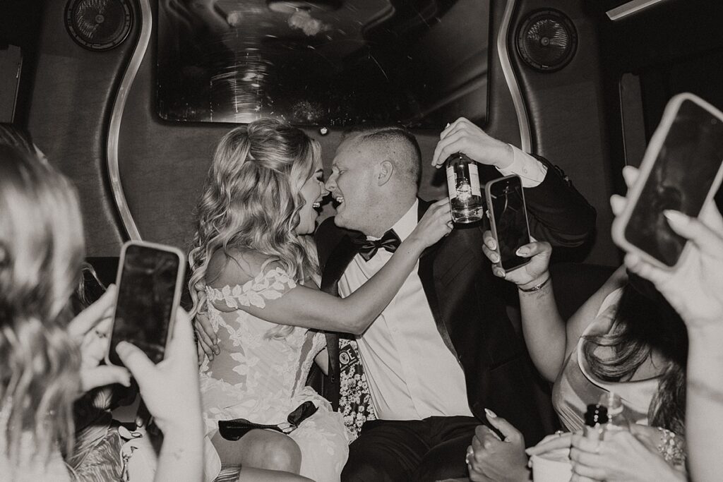 A black and white photo shows a bride and groom celebrating in a party bus on the way to their ceremony at lakeside wedding and events in Vegas