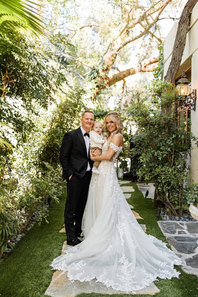 Newlyweds pose with their child at their Vegas elopement at lakeside wedding and events
