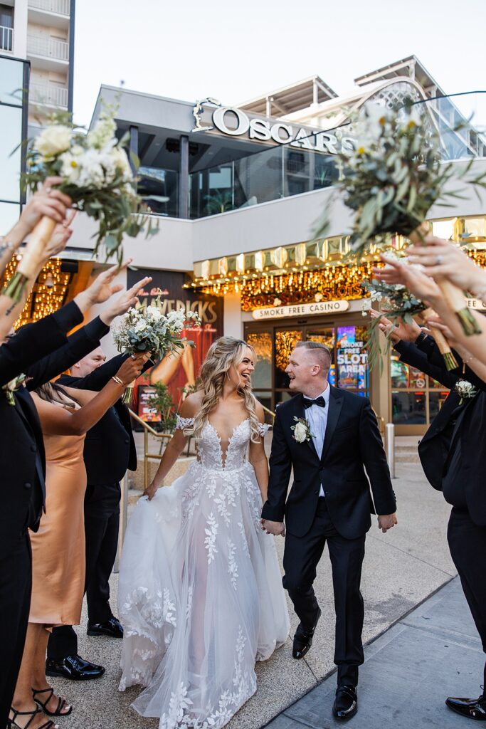 Newlyweds hold hands as they walk between their bridal party following their Las Vegas elopement 