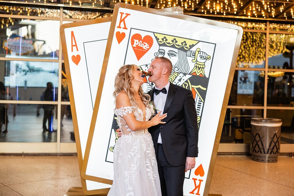Newlyweds pose for bridal portaits with cigars before playing card signs following their Las Vegas elopement